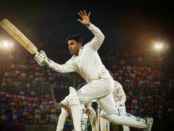 m444 Cricketer in white plays a shot under floodlights in a packed stadium