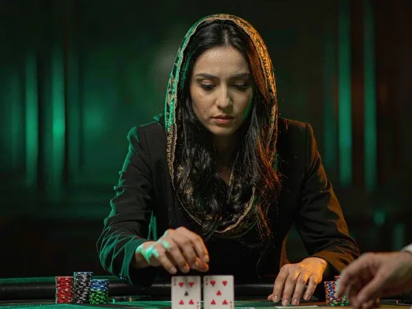 m444 Woman focuses on two face-up cards at a blackjack table with stacked chips