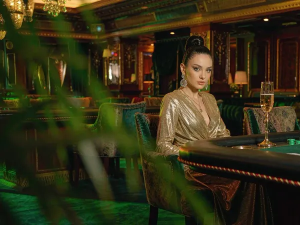 m444 Woman in a gold gown seated at a baccarat table in a VIP lounge